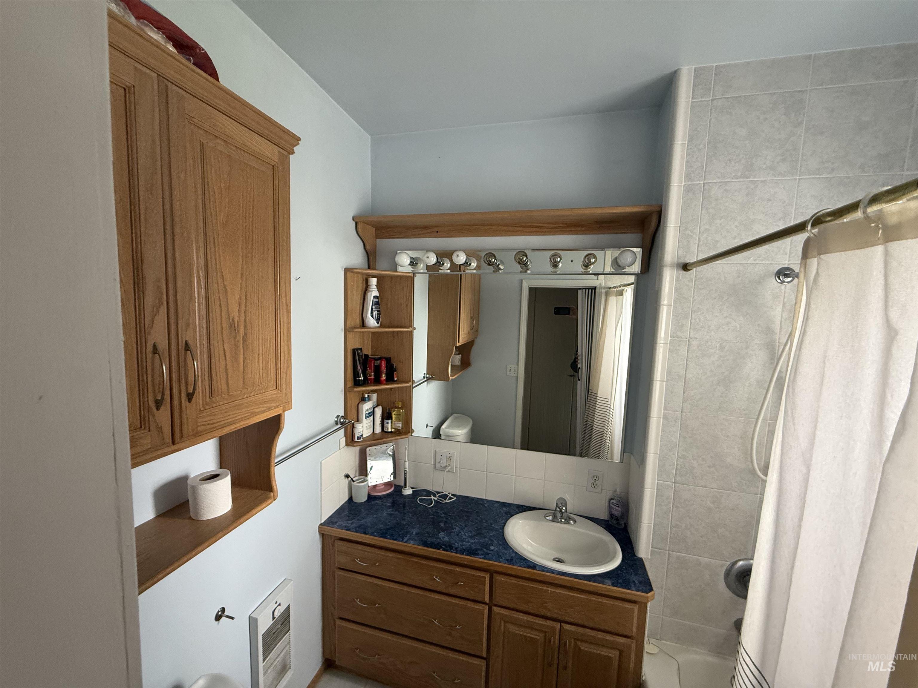 918 5th Street Rupert, ID 83350 - Photo 9 of 14 Full bath featuring heating unit, vanity, shower / bathtub combination with curtain, and backsplash