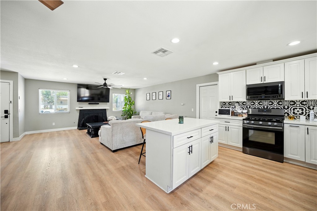 811 West James Street Rialto, CA 92376 - Photo 13 of 43 a large white kitchen with a stove top oven a sink dishwasher and a fireplace with wooden floor