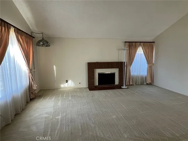 an empty room with windows a fireplace and a wooden floor