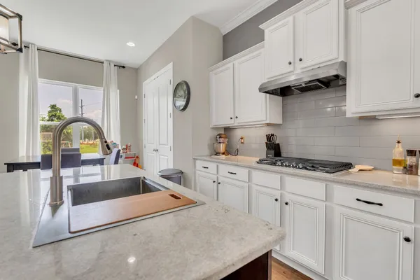 a kitchen with granite countertop a sink a stove and cabinets
