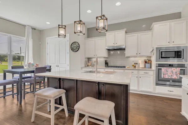 a large kitchen with granite countertop a table chairs sink and cabinets