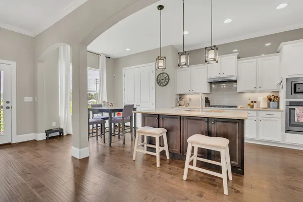a kitchen with stainless steel appliances granite countertop a table chairs sink and cabinets