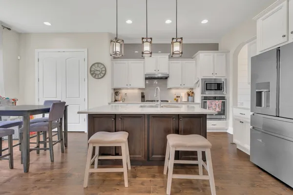 a kitchen with stainless steel appliances kitchen island granite countertop a table chairs sink and cabinets