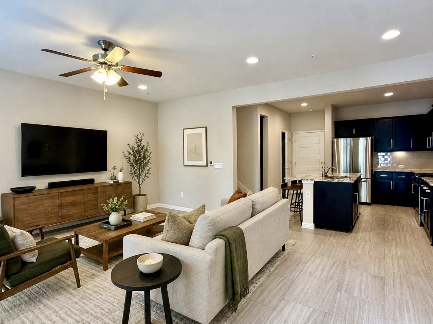*Virtually Staged. Open-concept living space featuring wood-finish tile flooring, recessed lighting, and a ceiling fan