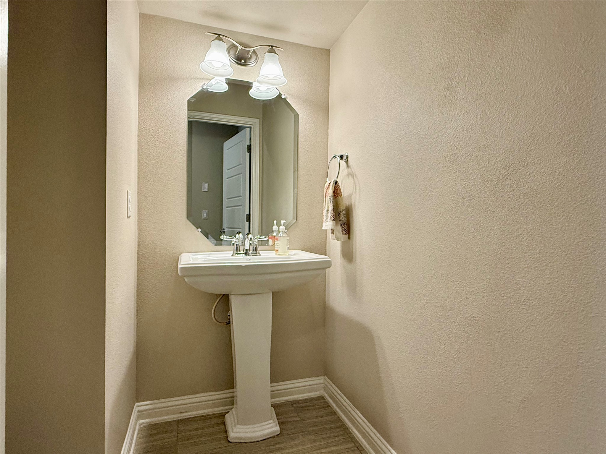 6814 East Riverside Drive, Unit 73 Austin, TX 78741 - Photo 13 of 33 Pedestal sink with chrome fixtures, an octagonal mirror, and a three-light vanity fixture