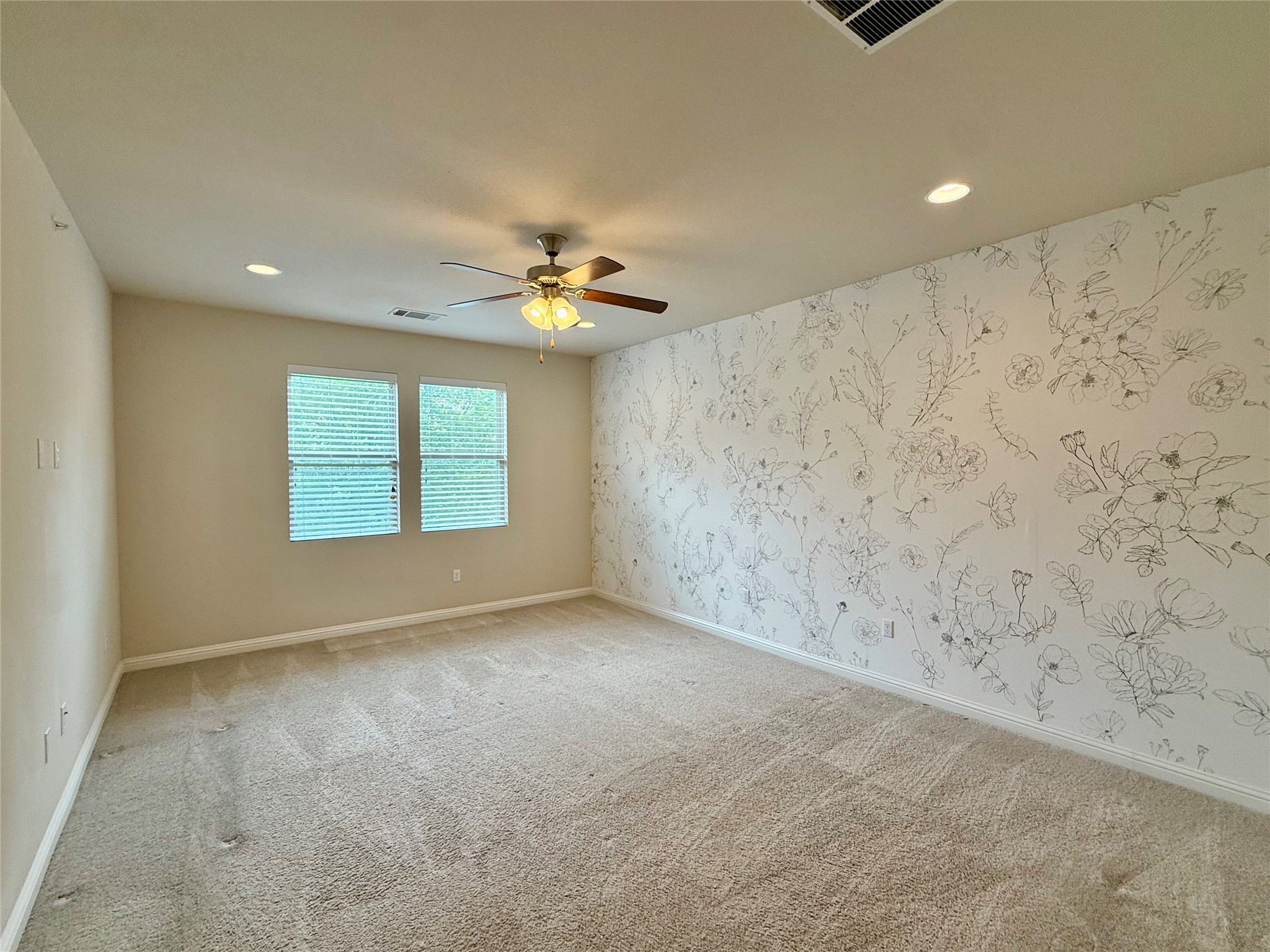 6814 East Riverside Drive, Unit 73 Austin, TX 78741 - Photo 15 of 33 Spacious room featuring accent wall with botanical pattern, neutral carpeting, recessed lighting, ceiling fan with light fixture, and two windows with blinds