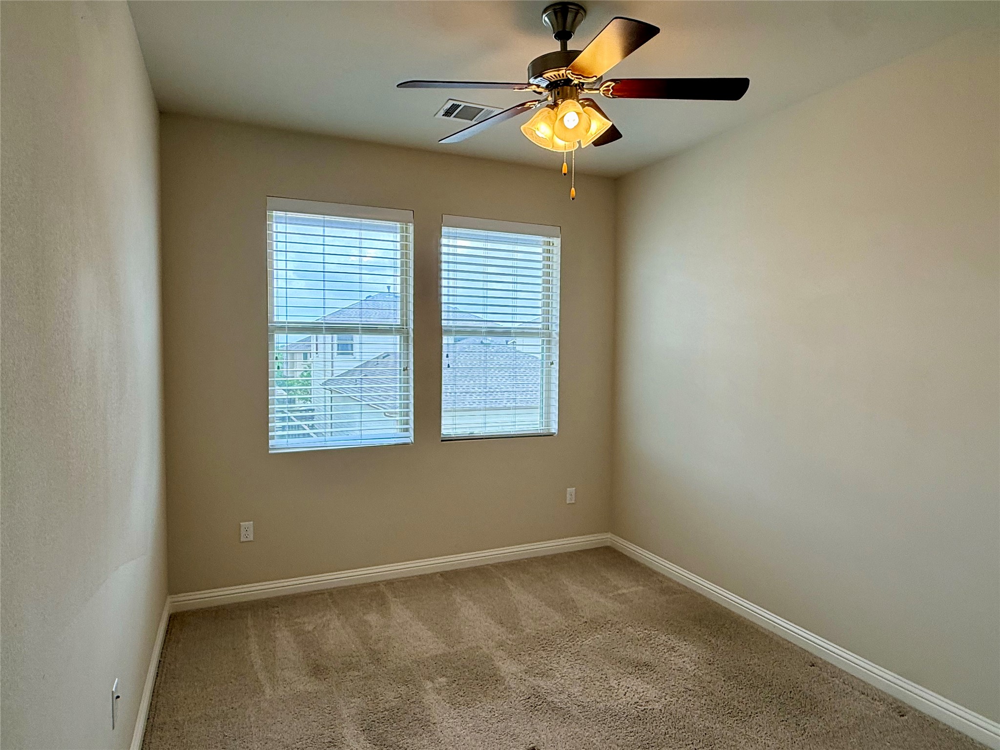 6814 East Riverside Drive, Unit 73 Austin, TX 78741 - Photo 25 of 33 Carpeted interior room featuring two windows with blinds, a ceiling fan with integrated lighting, and neutral wall tones
