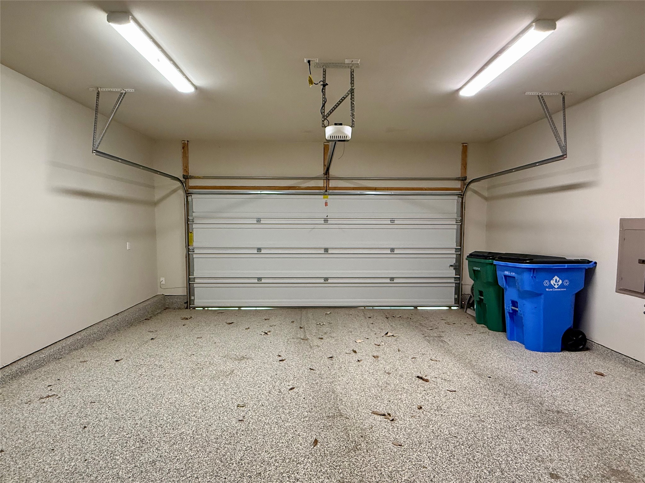 6814 East Riverside Drive, Unit 73 Austin, TX 78741 - Photo 30 of 33 Spacious garage featuring a white sectional door, speckled epoxy flooring, and two linear ceiling light fixtures