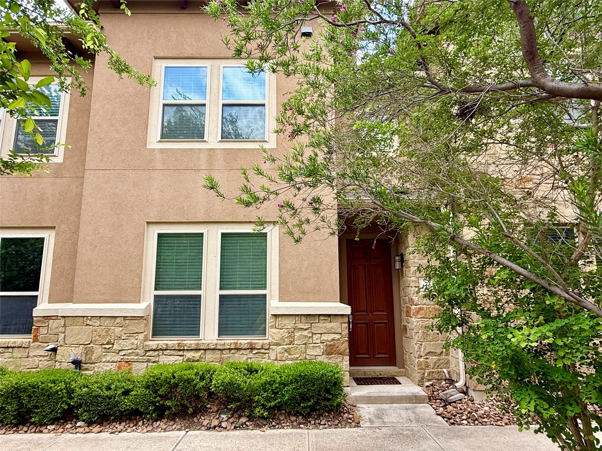 6814 East Riverside Drive, Unit 73 Austin, TX 78741 - Photo 3 of 33 Contemporary multi-story exterior featuring a stucco facade with stone accents, a paneled wood entry door, and a concrete pathway