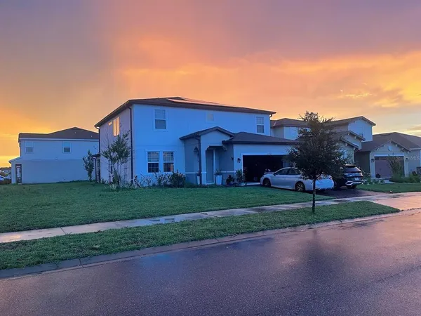a view of a house with a big yard plants and large trees