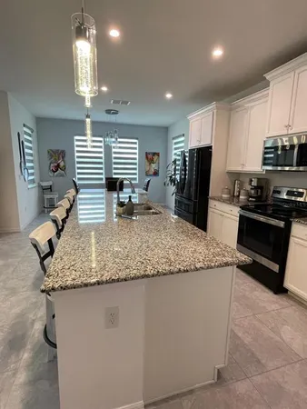 a kitchen with stainless steel appliances granite countertop a sink a stove a refrigerator cabinets and chairs