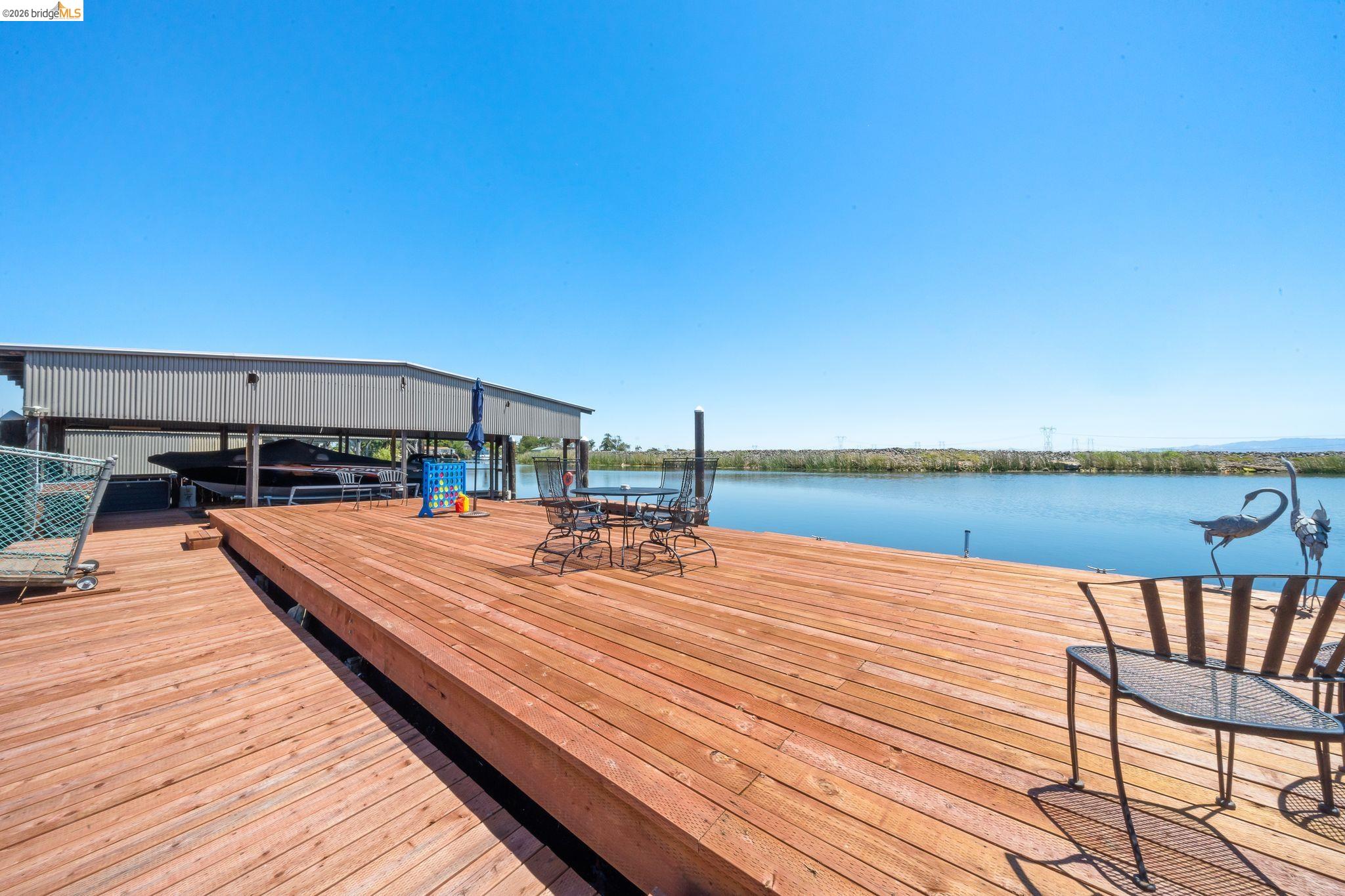 1704 Taylor Road Bethel Island, CA 94511 - Photo 53 of 73 Expansive wood deck with water frontage, featuring a built-in boat house with metal siding, and a clear view of the open water