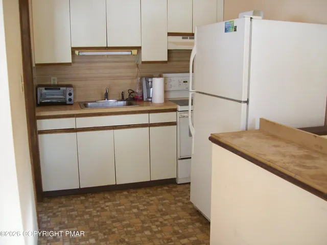 a kitchen with a sink a refrigerator and cabinets