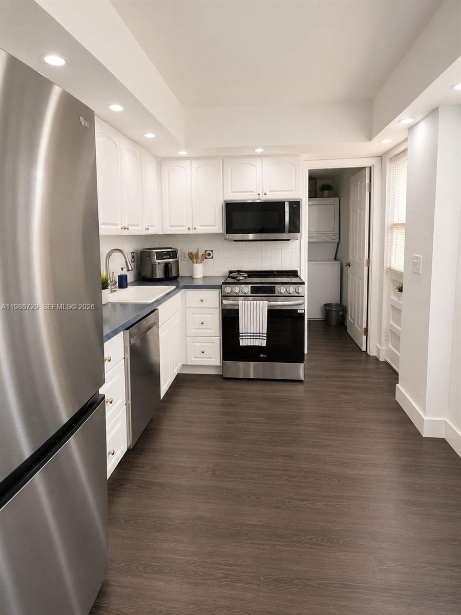 299 Northwest 52nd Terrace, Unit PHX Boca Raton, FL 33487 - Photo 5 of 16 a large kitchen with stainless steel appliances granite countertop a stove top oven a sink a refrigerator and white cabinets with wooden floor