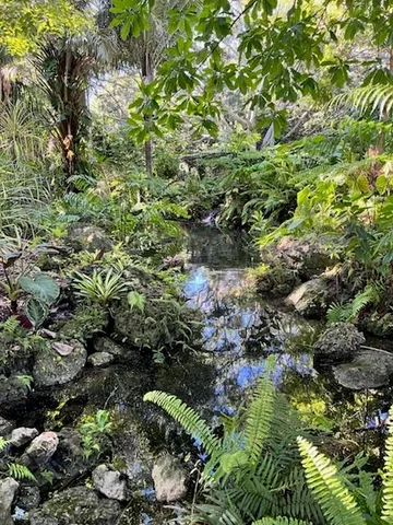 a view of a sign in front of a house with a garden