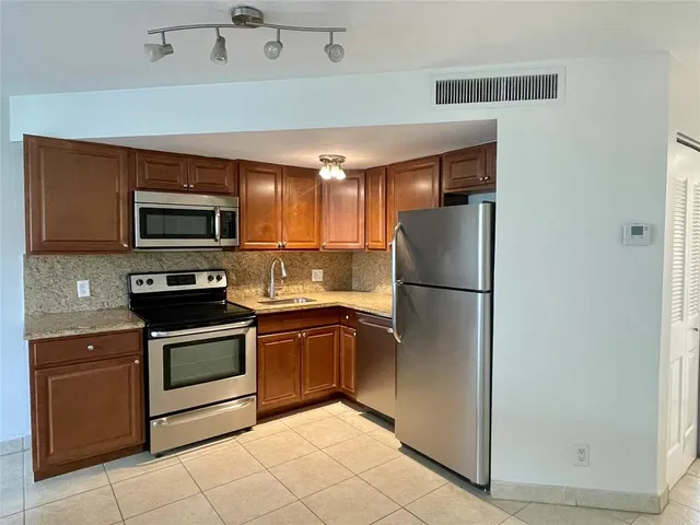 a kitchen with stainless steel appliances kitchen island granite countertop a refrigerator and a stove