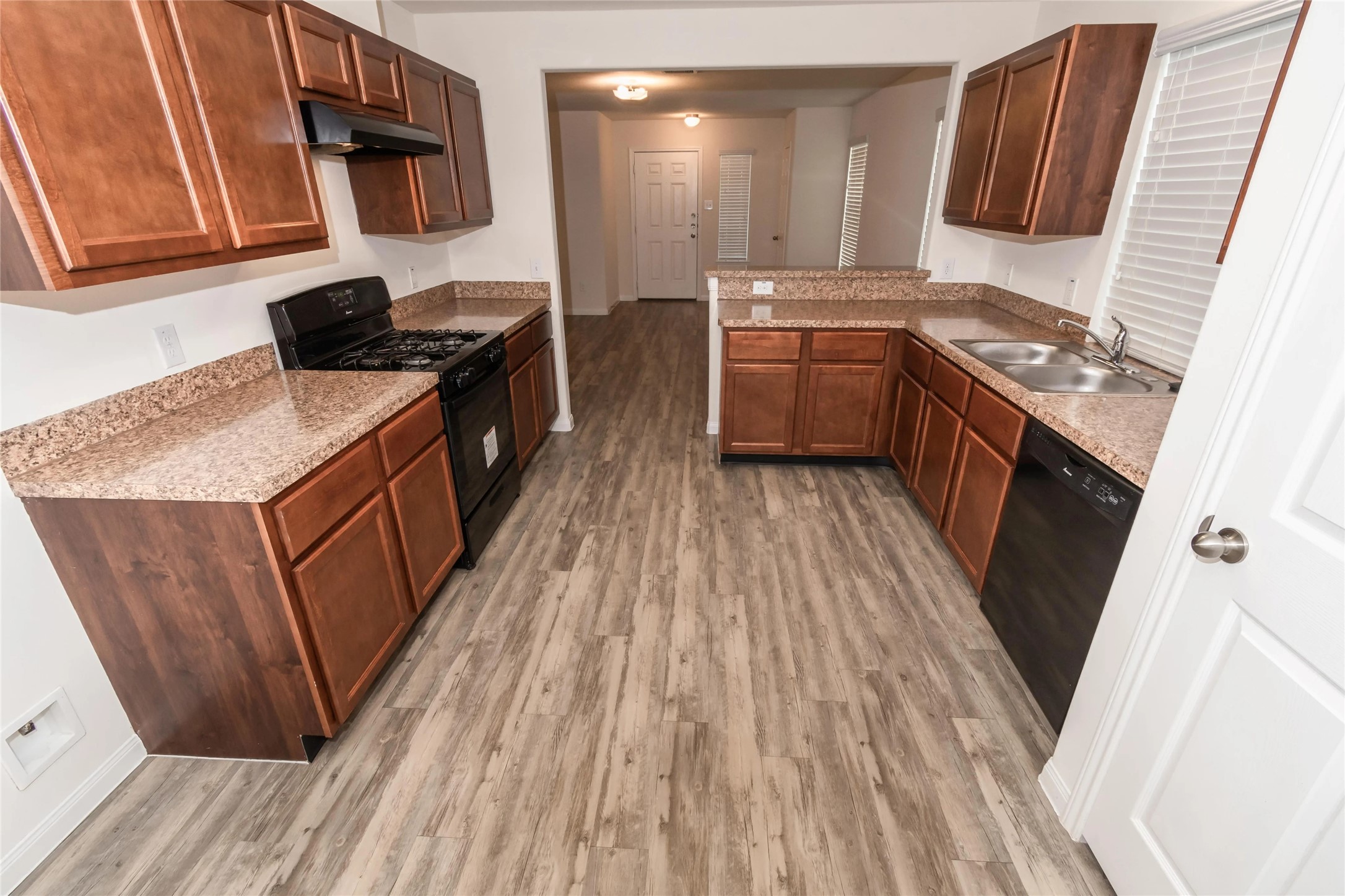 a kitchen with a sink stove top oven and wooden floor