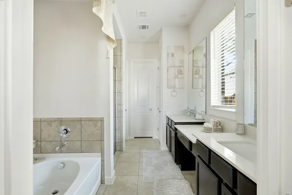a spacious bathroom with a tub sink shower and mirror