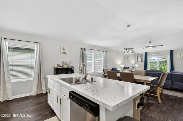 a kitchen with stainless steel appliances granite countertop a dining table chairs refrigerator and microwave