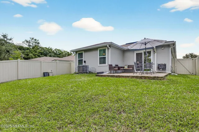 a view of a white house with a small yard plants and a large tree