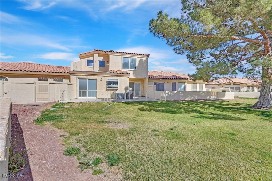 5421 Painted Mirage Road Las Vegas, NV 89149 - Photo 23 of 35 Rear view of house featuring fence private yard, a tiled roof, a lawn, and stucco siding