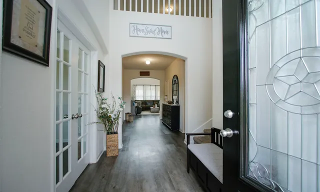 a hallway with couches and dining table with wooden floor