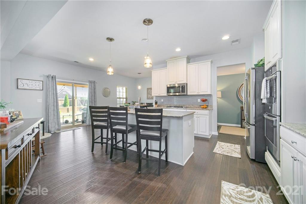 2159 Stone Pile Drive Concord, NC 28025 - Photo 4 of 33 a kitchen with stainless steel appliances granite countertop a refrigerator a stove top oven a sink dishwasher a dining table and chairs with wooden floor