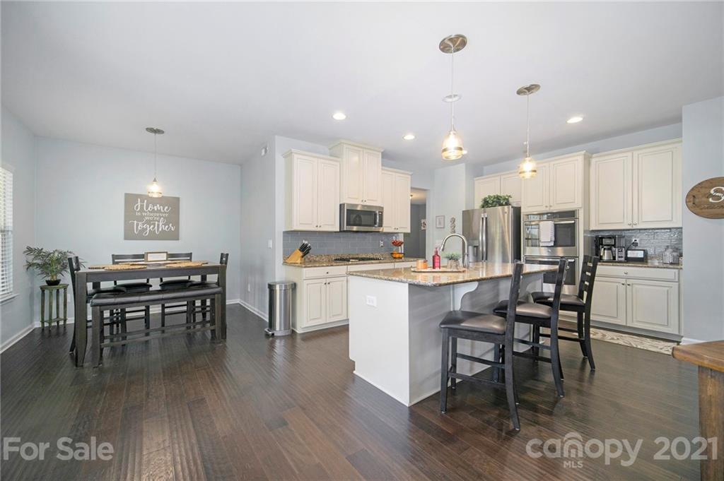 2159 Stone Pile Drive Concord, NC 28025 - Photo 6 of 33 a kitchen with a dining table chairs wooden floor appliances and cabinets