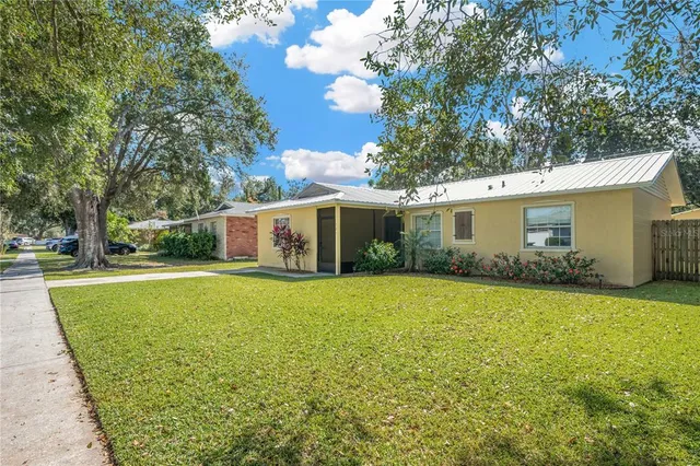 a view of a white house with a yard and a large tree