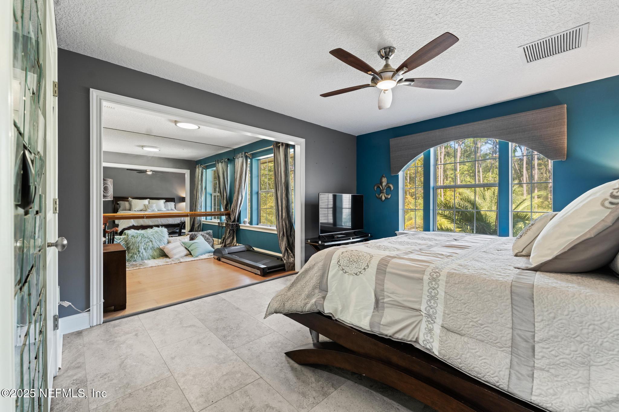 3010 Starratt Road Jacksonville, FL 32226 - Photo 70 of 106 a bedroom with a balcony a bed and a large window with a chandelier