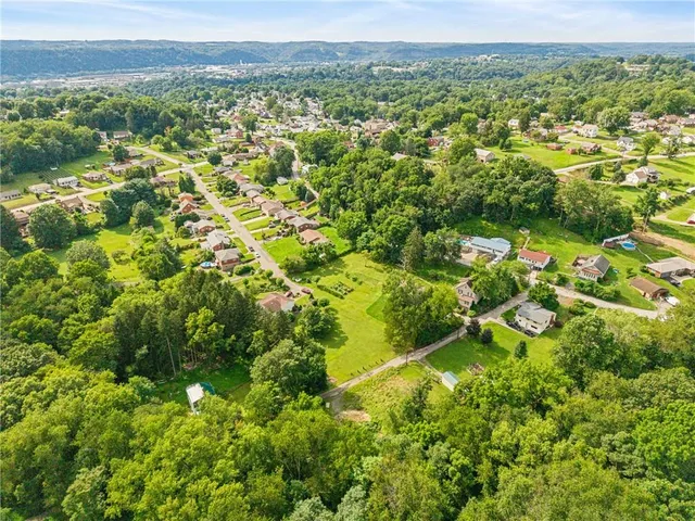 an aerial view of residential houses with outdoor space and trees