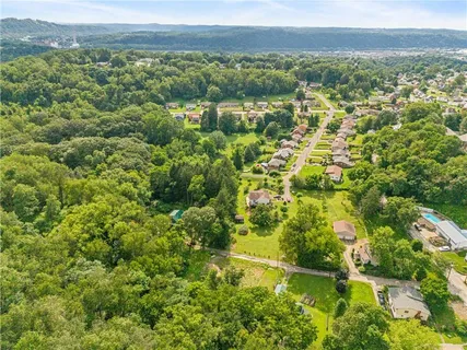 an aerial view of residential houses with outdoor space and trees