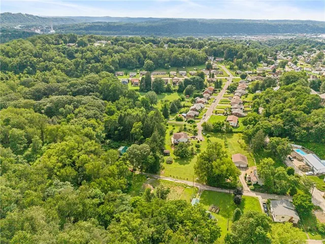 an aerial view of residential houses with outdoor space and trees