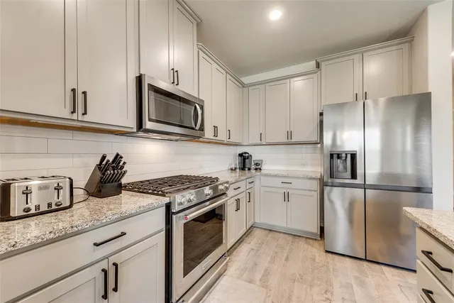 a kitchen with granite countertop cabinets stainless steel appliances and a counter space