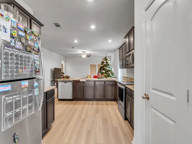 a kitchen with stainless steel appliances a large counter top a stove top oven a sink and a refrigerator