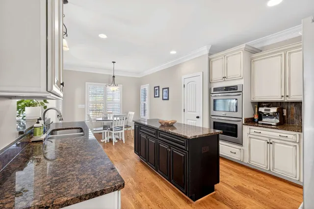 a kitchen with stainless steel appliances granite countertop a stove top oven a sink a dining table and chairs