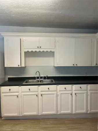 a kitchen with granite countertop white cabinets and a sink