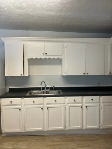 a kitchen with granite countertop white cabinets and a sink