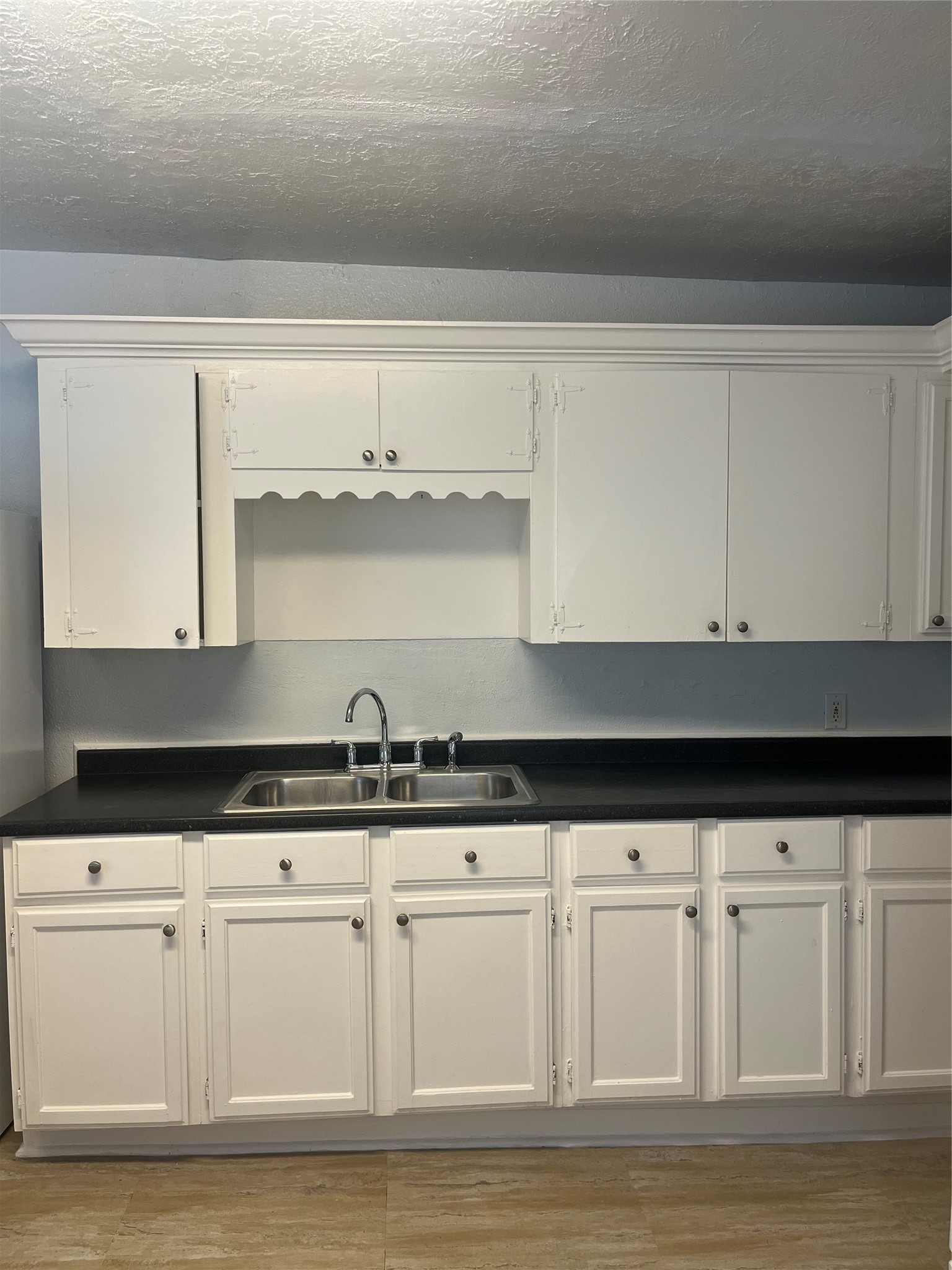 a kitchen with granite countertop white cabinets and a sink