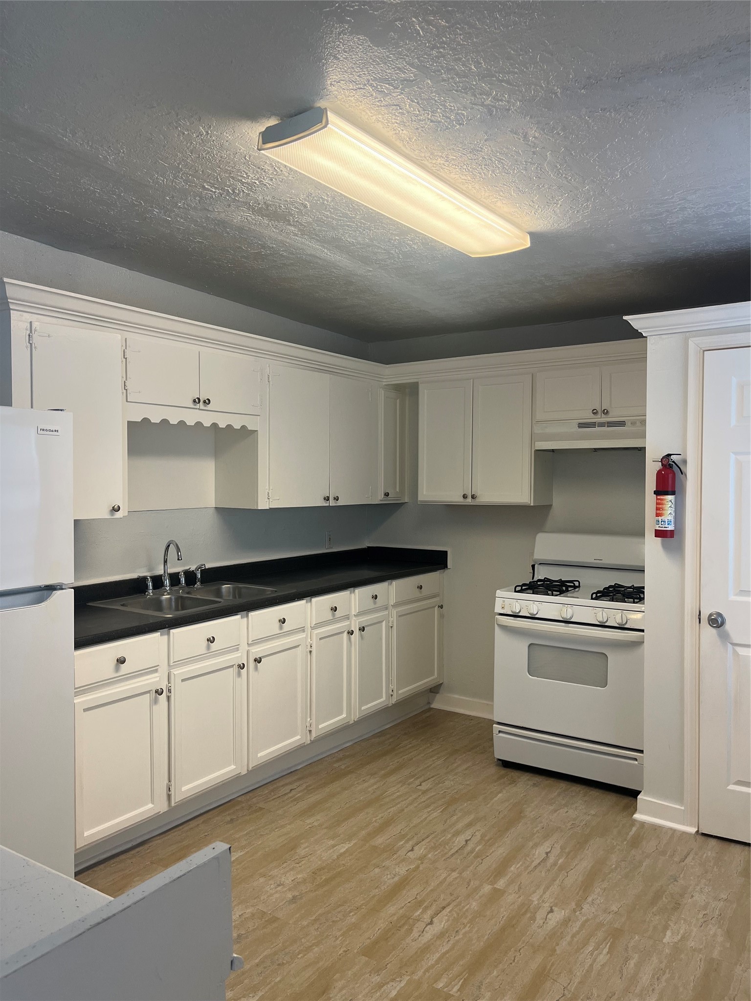 5537 Bataan Road, Unit B Houston, TX 77033 - Photo 3 of 13 a kitchen with granite countertop white cabinets and white appliances