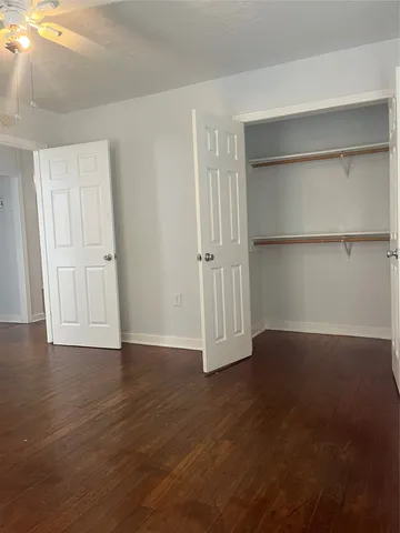 a view of an empty room with wooden floor and closet