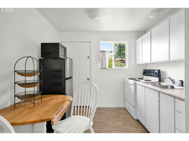 a kitchen with a refrigerator a stove a sink dishwasher a dining table and chair with wooden floor