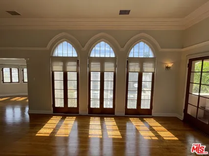 a view of an empty room with wooden floor and a window