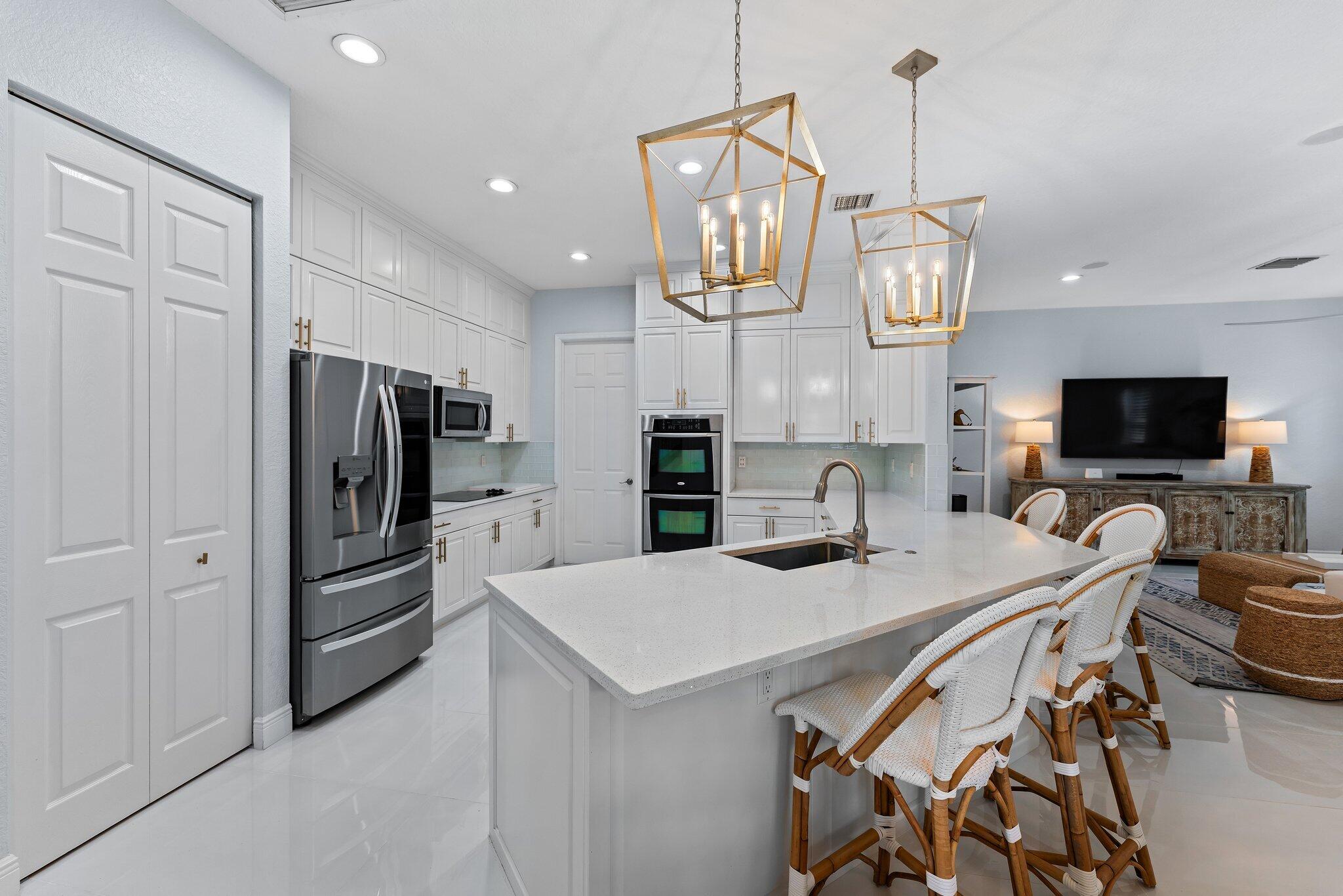 108 Via Azurra Jupiter, FL 33458 - Photo 21 of 78 a kitchen with stainless steel appliances kitchen island granite countertop a refrigerator a sink dishwasher a stove and a dining table with wooden floor