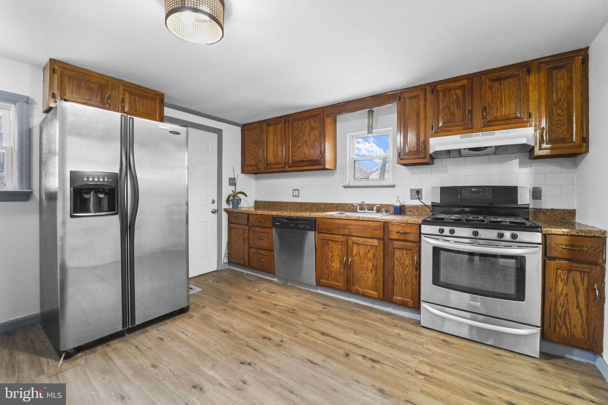 85 East 9th Avenue Pine Hill, NJ 08021 - Photo 11 of 27 a kitchen with stainless steel appliances granite countertop a stove a refrigerator and a sink with wooden floor