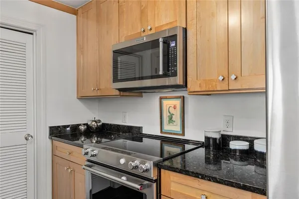 a kitchen with granite countertop a stove a microwave a sink and white cabinets