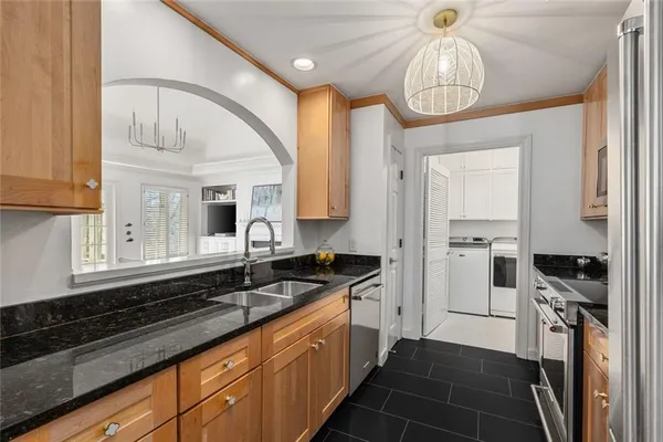 a kitchen with granite countertop a sink a counter space appliances and cabinets