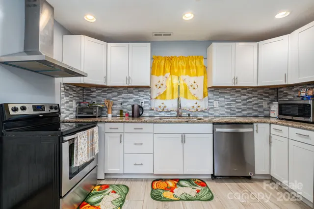 a kitchen with stainless steel appliances granite countertop a sink a stove and a refrigerator
