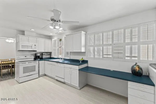 a kitchen with granite countertop a stove a sink and white cabinets