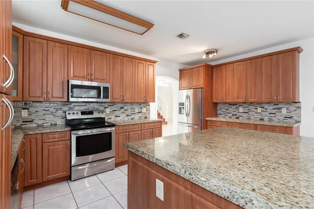 a kitchen with stainless steel appliances granite countertop wooden cabinets a stove top oven a sink and dishwasher